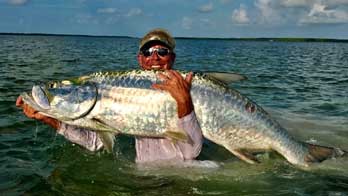 Capt Larry Sydnor holding huge tarpon in water